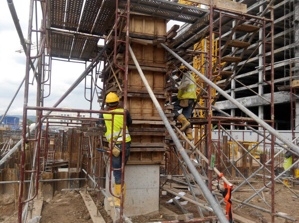  Construction workers fabricating column timber form work and reinforcement bar