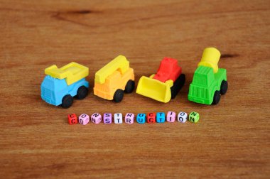 Ahşap doku arka plan üzerinde sentetik kauçuk yapılmış inşaat ağır makine minyatür modeli. Ortadaki küçük plastik blok üzerine basılmış inşaat metni.  