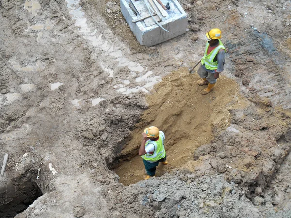 Trabalhadores da construção civil fixação de tubos subterrâneos — Fotografia de Stock