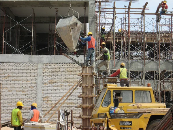 Kuala Lumpur, Malezya-16 Eylül 2016: Grup inşaat sahasında kereste formu işe Vinç kovası kullanarak ıslak beton dökme inşaat işçileri.  