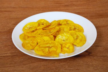 Kurutulmuş ve ahşap doku arka plan üzerinde beyaz plaka üzerinde kızarmış muz dilimleri yer izole. Bu yerel Malaysian geleneksel abur cubur çağrı havuçlu Pisang mı. 