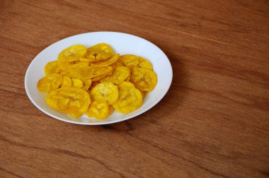 Kurutulmuş ve ahşap doku arka plan üzerinde beyaz plaka üzerinde kızarmış muz dilimleri yer izole. Bu yerel Malaysian geleneksel abur cubur çağrı havuçlu Pisang mı. 