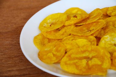 Kurutulmuş ve ahşap doku arka plan üzerinde beyaz plaka üzerinde kızarmış muz dilimleri yer izole. Bu yerel Malaysian geleneksel abur cubur çağrı havuçlu Pisang mı. 