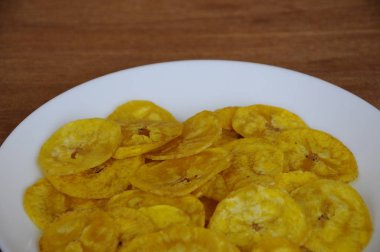 Kurutulmuş ve ahşap doku arka plan üzerinde beyaz plaka üzerinde kızarmış muz dilimleri yer izole. Bu yerel Malaysian geleneksel abur cubur çağrı havuçlu Pisang mı. 