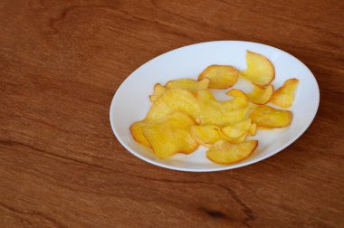 Kurutulmuş ve ahşap doku arka plan üzerinde beyaz plaka üzerinde kızarmış manyok dilimleri yer izole. Bu yerel Malaysian geleneksel abur cubur çağrı havuçlu Ubi mı.