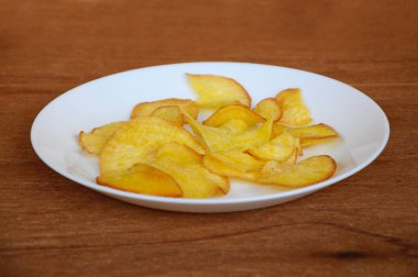 Kurutulmuş ve ahşap doku arka plan üzerinde beyaz plaka üzerinde kızarmış manyok dilimleri yer izole. Bu yerel Malaysian geleneksel abur cubur çağrı havuçlu Ubi mı.