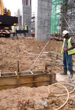 JOHOR, MALAYSIA - 29 Mart 2016: İnşaat işçileri termit karşıtı kimyasal tedaviyi inşaat alanındaki toprağa püskürtüyorlar. 