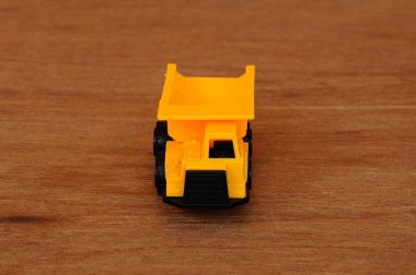 Küçük ağır inşaat makine oyuncak, kamyonet. Bir ahşap tahıl doku arka plan üzerinde izole plastik.