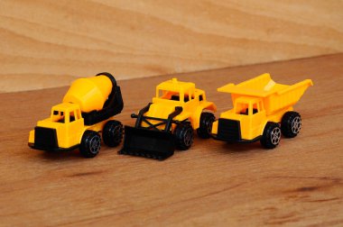 Küçük bir inşaat makinesi oyuncağı, kamyon, buldozer ve beton karıştırıcı grubu. Hepsi de ahşap dokuda izole edilmiş plastikten yapılmış..