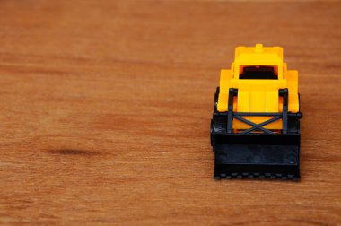 Küçük ağır inşaat makine oyuncak, buldozer. Tüm plastik ahşap tahıl doku arka plan üzerinde izole.
