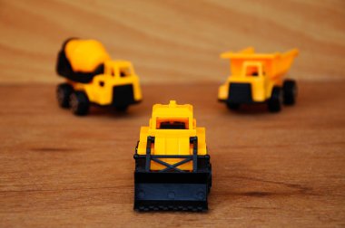 Küçük bir inşaat makinesi oyuncağı, kamyon, buldozer ve beton karıştırıcı grubu. Hepsi de ahşap dokuda izole edilmiş plastikten yapılmış..