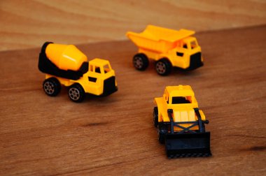 Küçük bir inşaat makinesi oyuncağı, kamyon, buldozer ve beton karıştırıcı grubu. Hepsi de ahşap dokuda izole edilmiş plastikten yapılmış..