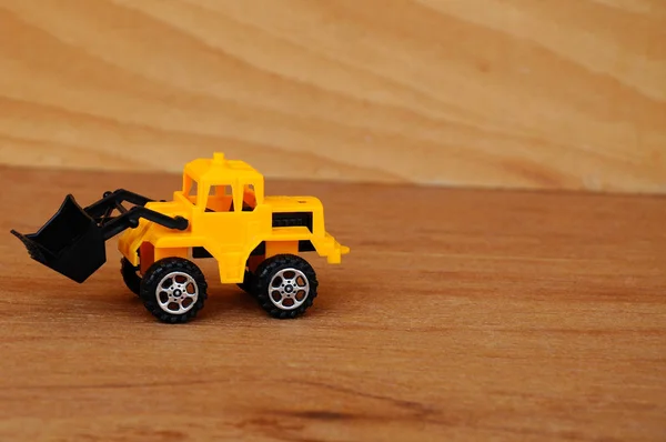 小さな重建設機械おもちゃ ブルドーザー すべてのプラスチック製の木目テクスチャ背景に分離 — ストック写真