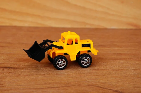 小さな重建設機械おもちゃ ブルドーザー すべてのプラスチック製の木目テクスチャ背景に分離 — ストック写真