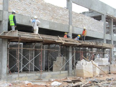 KUALA LUMPUR, MALAYSIA - 14 Temmuz 2016: İnşaat işçileri inşaat sahasına kil tuğla döşeyerek duvar oluşturdular. Tuğla, çimento harcı kullanarak birbirine yapışır.. 