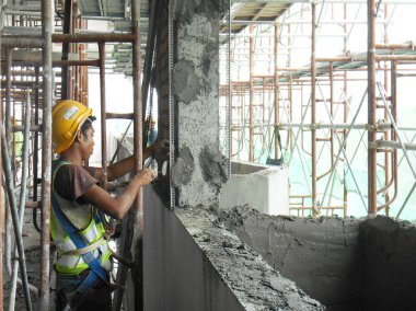 JASIN, MALAYSIA -14 HAZİRAN 2017: Malezya 'nın Jasin kentindeki inşaat sahasında çimento ve kum karışımı kullanarak inşaat duvarlarını ve kirişleri alçılayan inşaat işçileri