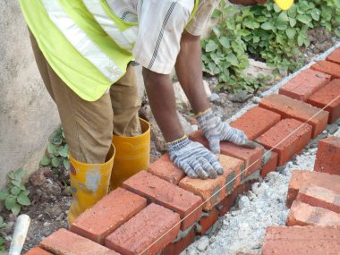 KUALA LUMPUR, MALAYSIA - 14 Temmuz 2016: İnşaat işçileri inşaat sahasına kil tuğla döşeyerek duvar oluşturdular. Tuğla, çimento harcı kullanarak birbirine yapışır.. 
