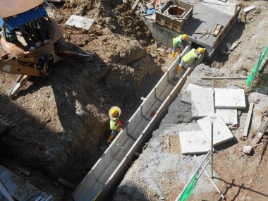İnşaat İşçileri inşaat sahasında prekast yeraltı drenaj yüklemek.