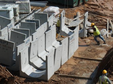 İnşaat İşçileri inşaat sahasında prekast yeraltı drenaj yüklemek.