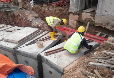 İnşaat İşçileri inşaat sahasında prekast yeraltı drenaj yüklemek.