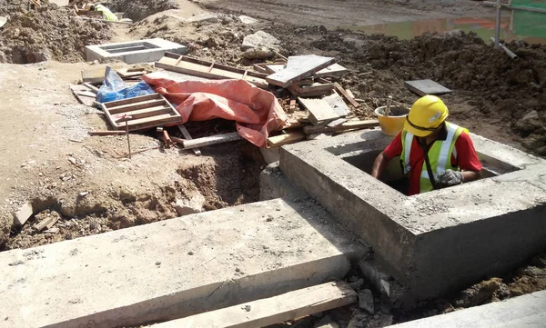 Trabajadores de la construcción instalan drenaje subterráneo prefabricado en el sitio de construcción . — Foto de Stock