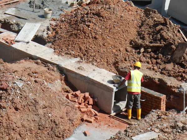 Trabajadores de la construcción instalan drenaje subterráneo prefabricado en el sitio de construcción . — Foto de Stock