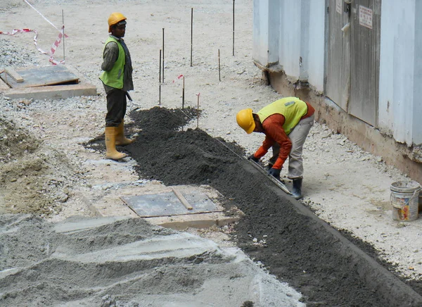 Travailleurs de la construction fabriquant bordure de route en béton sur le site de construction . — Photo