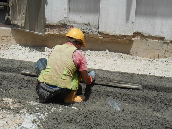 Stavební dělníci zhotovení betonové silniční obrubník na staveništi. — Stock fotografie