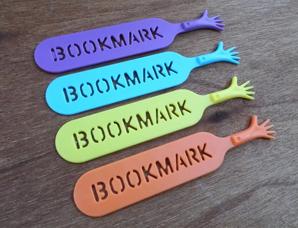 Colorful plastic bookmark used to mark reading location after stop reading the book. It was design with image of colorfull hand and has word \'bookmark\' on it.