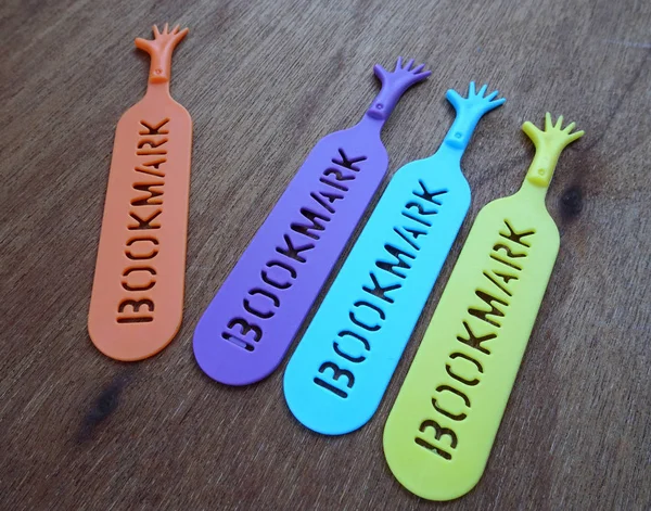 Colorful plastic bookmark used to mark reading location after stop reading the book. It was design with image of colorfull hand and has word 'bookmark' on it.