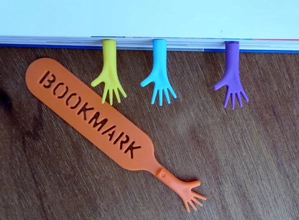 Colorful plastic bookmark used to mark reading location after stop reading the book. It was design with image of colorfull hand and has word \'bookmark\' on it.