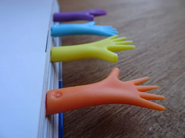 Colorful plastic bookmark used to mark reading location after stop reading the book. It was design with image of colorfull hand and has word 'bookmark' on it.