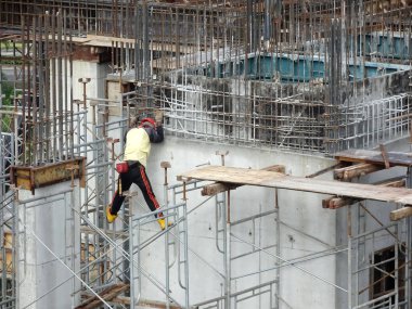 Kuala Lumpur, Malezya-07 Temmuz 2017: inşaat işçileri yükseklikte inşaat alanında çalışıyor. İskele geçici platformu olarak çalışmak için kullanma. Onlar uygun güvenlik dişli giymek için gerekli olan. 