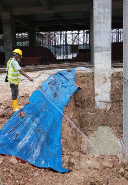 Kuala Lumpur, Malezya - 29 Haziran 2017: İnşaat işçileri termit karşıtı kimyasal tedaviyi inşaat alanındaki toprağa karıştırıp püskürtüyorlar. 