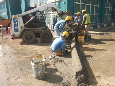 KUALA LUMPUR, MALAYSIA -NOVEMBER 02, 2018: Construction workers fabricating concrete road kerb at the construction site. They are using the in-situ method using the standard metal mould. 