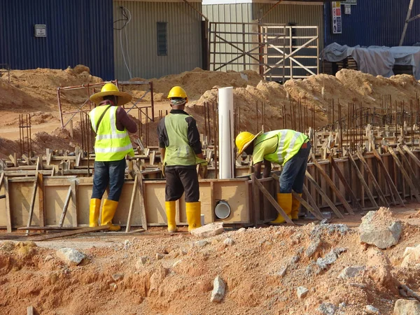 KUALA LUMPUR, MALAYSIA -MARCH, 2019: Construction workers installing & fabricating ground beam timber form works at the construction site. The formworks made from timber and plywood. 