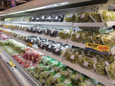 Kuala Lumpur, Malezya - 26 Ekim 2019: Meyveler plastik kapta ve plastik ambalajda paketlenmiştir. Büyük süpermarketin içindeki soğutucu rafında satılık.. 