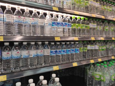 Kuala Lumpur, Malezya - 26 Ekim 2019: Maden suyu paketlendi ve plastik şişelerde çeşitli markalarla etiketlendi. Süpermarketin içindeki bir rafta gösteriliyor.