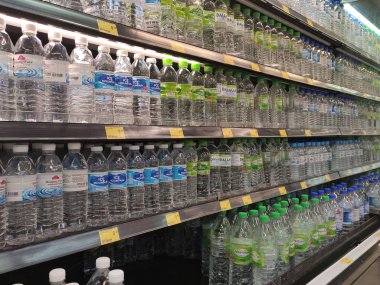 Kuala Lumpur, Malezya - 26 Ekim 2019: Maden suyu paketlendi ve plastik şişelerde çeşitli markalarla etiketlendi. Süpermarketin içindeki bir rafta gösteriliyor.