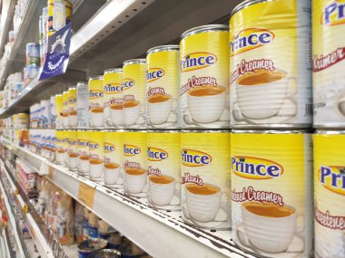 Kuala Lumpur, Malezya - 22 Aralık 2019: Şekerli krema ve buharlaştırılmış süt kutular içinde paketlenmiş ve süpermarketin içindeki rafta satılmak üzere sergilenmektedir. Ana bileşen palmiye yağı tohumlarından yapılır..