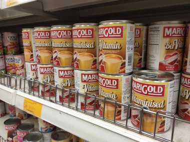 Kuala Lumpur, Malezya - 22 Aralık 2019: Şekerli krema ve buharlaştırılmış süt kutular içinde paketlenmiş ve süpermarketin içindeki rafta satılmak üzere sergilenmektedir. Ana bileşen palmiye yağı tohumlarından yapılır..