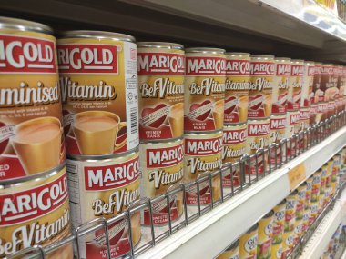 Kuala Lumpur, Malezya - 22 Aralık 2019: Şekerli krema ve buharlaştırılmış süt kutular içinde paketlenmiş ve süpermarketin içindeki rafta satılmak üzere sergilenmektedir. Ana bileşen palmiye yağı tohumlarından yapılır..