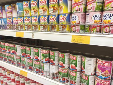 Kuala Lumpur, Malezya - 22 Aralık 2019: Şekerli krema ve buharlaştırılmış süt kutular içinde paketlenmiş ve süpermarketin içindeki rafta satılmak üzere sergilenmektedir. Ana bileşen palmiye yağı tohumlarından yapılır..