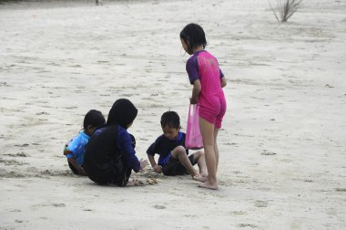 Mersing, Malezya - 6 Mart 2016: Kimliği belirsiz Asyalı çocuklar kumsalda kum oynuyorlar. Yüzme bezi giyiyor.. 