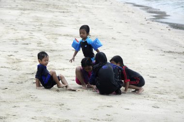 Mersing, Malezya - 6 Mart 2016: Kimliği belirsiz Asyalı çocuklar kumsalda kum oynuyorlar. Yüzme bezi giyiyor.. 
