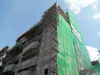 Kuala Lumpur, Malezya - 6 Haziran 2016: İnşaat altındaki binanın dış kısmına inşaat enkazının düşmesini önlemek için plastik veya naylon ağ örüldü. Geçici kurulum.