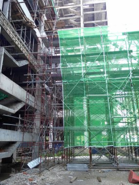 Kuala Lumpur, Malezya - 6 Haziran 2016: İnşaat altındaki binanın dış kısmına inşaat enkazının düşmesini önlemek için plastik veya naylon ağ örüldü. Geçici kurulum.