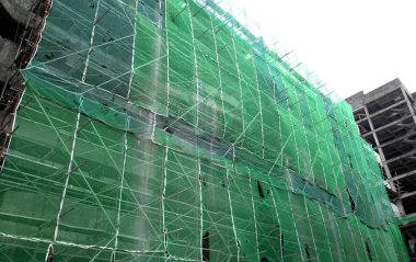 Kuala Lumpur, Malezya - 6 Haziran 2016: İnşaat altındaki binanın dış kısmına inşaat enkazının düşmesini önlemek için plastik veya naylon ağ örüldü. Geçici kurulum.