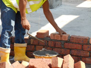 Johor, Malezya - 25 Kasım 2016: İnşaat alanında inşaat duvarları oluşturmak için tuğla döşeyen tuğla ustası. 