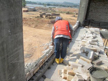 Johor, Malezya - 25 Kasım 2016: İnşaat alanında inşaat duvarları oluşturmak için tuğla döşeyen tuğla ustası. 
